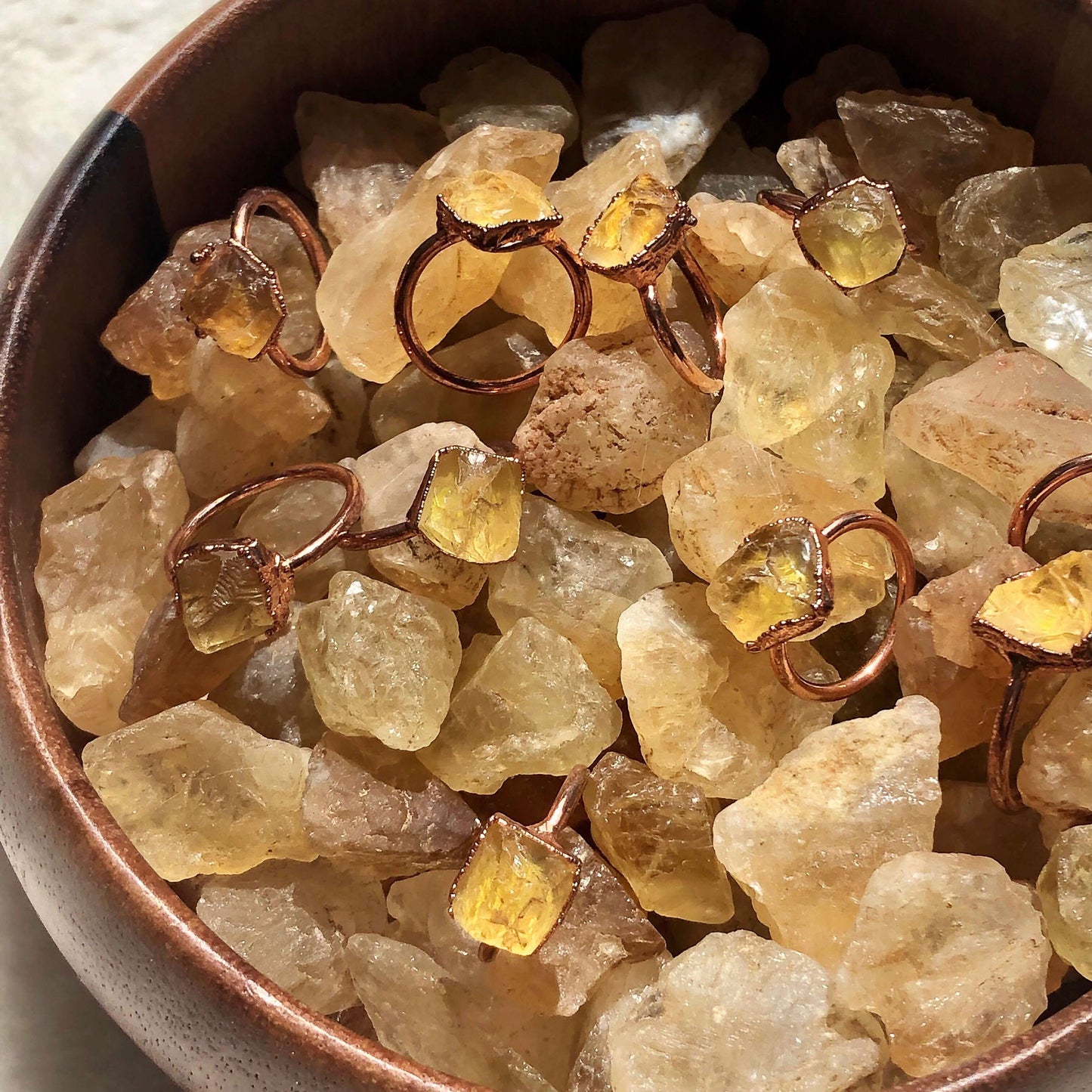 Citrine crystals together in a wooden bowl with rings on top