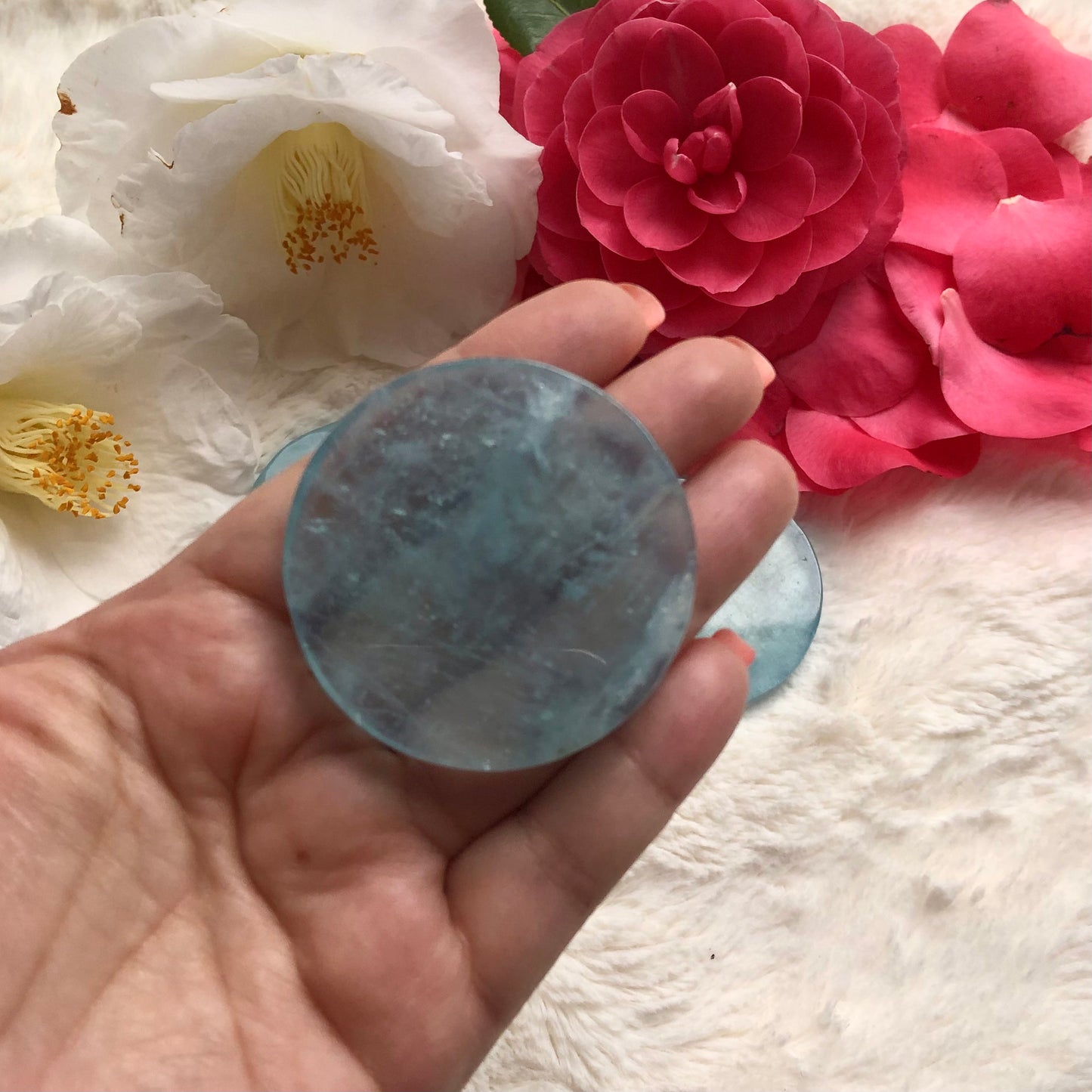 Aquamarine blue disc crystal held in hand